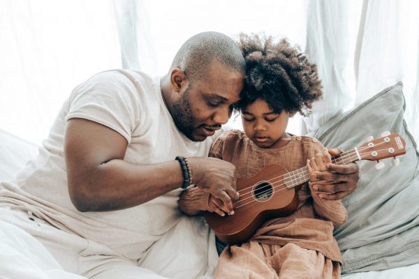 ethnic-father-teaching-kid-playing-on-ukulele-at-home-4545618